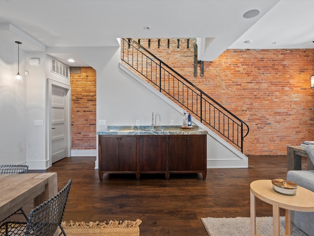 interior space featuring dark brown cabinetry, dark wood-type flooring, and brick wall