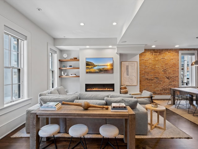 living room with dark wood-type flooring and brick wall