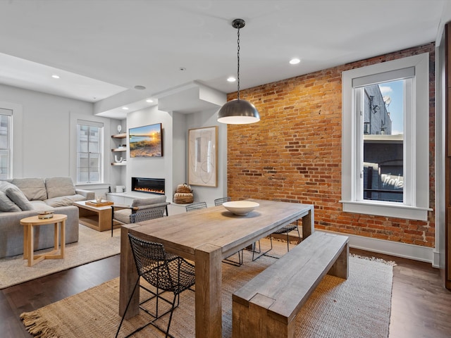 dining space featuring dark hardwood / wood-style floors and brick wall