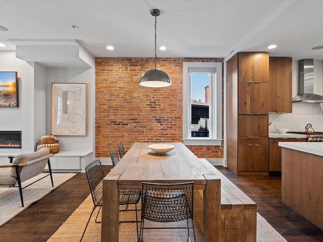 dining space featuring dark wood-type flooring and brick wall