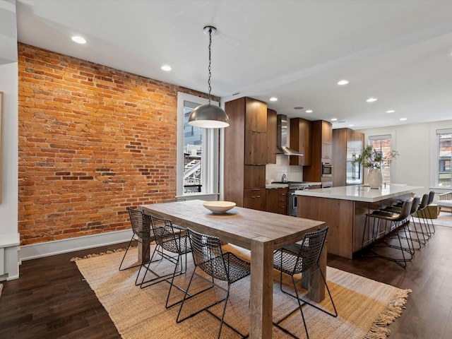 dining room featuring dark hardwood / wood-style floors and brick wall