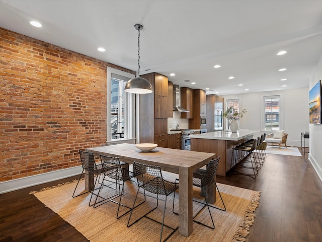 dining space with dark hardwood / wood-style flooring and brick wall