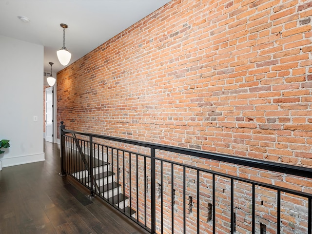 hallway with dark wood-type flooring and brick wall