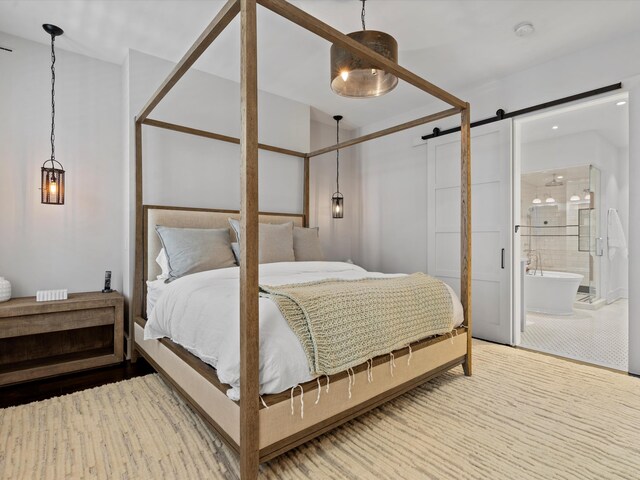 bedroom with connected bathroom, a barn door, ceiling fan, and carpet flooring