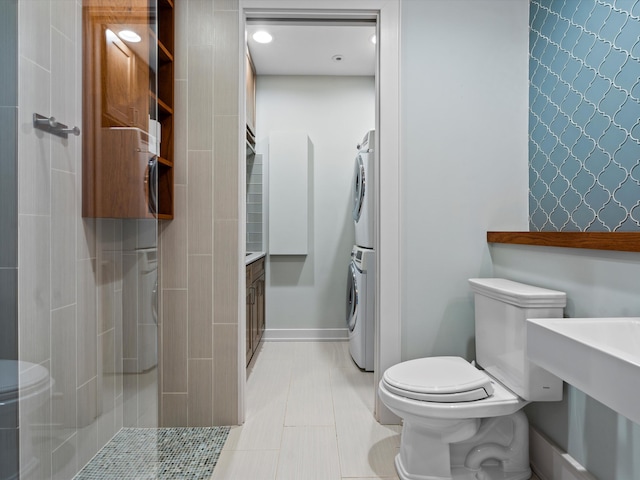 bathroom with tile patterned floors, walk in shower, sink, toilet, and stacked washer / drying machine