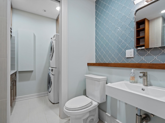 bathroom with tile patterned floors, sink, toilet, and stacked washer and dryer