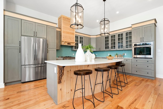 kitchen featuring a center island, backsplash, gray cabinets, appliances with stainless steel finishes, and light hardwood / wood-style floors