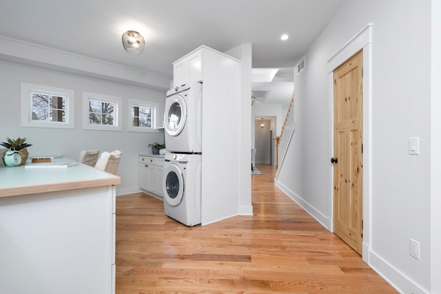 washroom with light hardwood / wood-style flooring and stacked washer / dryer