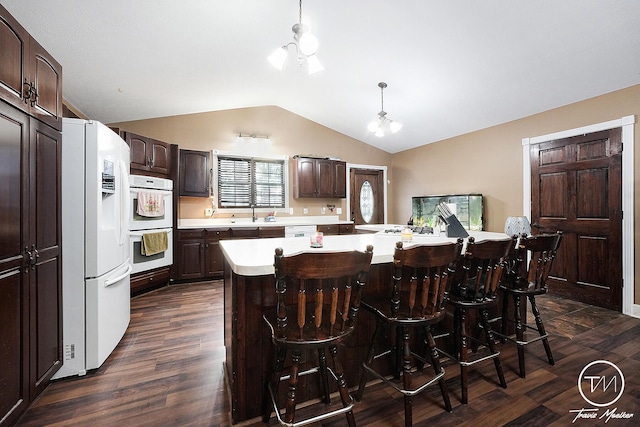 kitchen featuring white appliances, lofted ceiling, dark hardwood / wood-style floors, a kitchen island, and a chandelier