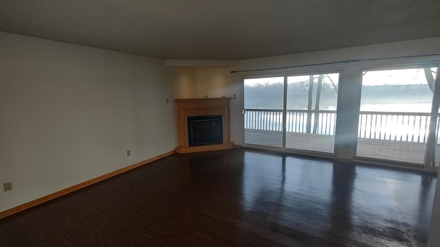 unfurnished living room with dark hardwood / wood-style floors, a healthy amount of sunlight, and a water view