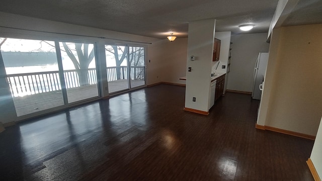 empty room with a water view, dark wood-type flooring, and a textured ceiling