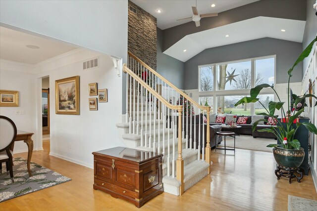 stairway featuring wood-type flooring, ornamental molding, ceiling fan, and lofted ceiling