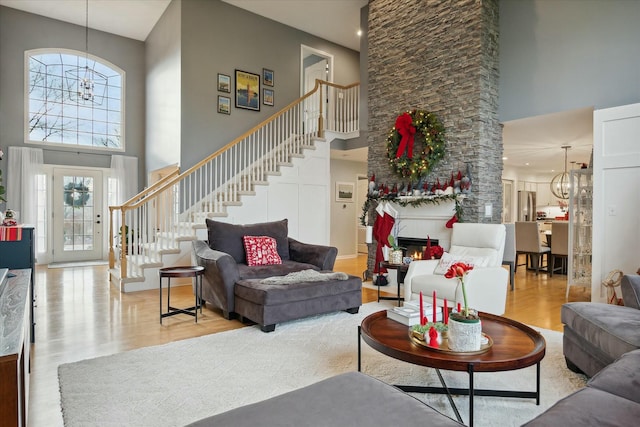 living room featuring light wood-type flooring, a high ceiling, and an inviting chandelier