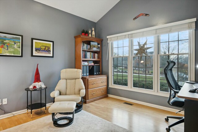 home office with light hardwood / wood-style floors and lofted ceiling