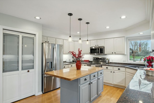 kitchen with wood counters, white cabinets, sink, appliances with stainless steel finishes, and a kitchen island