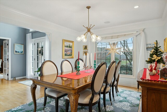 dining area featuring a notable chandelier, french doors, ornamental molding, and light hardwood / wood-style flooring