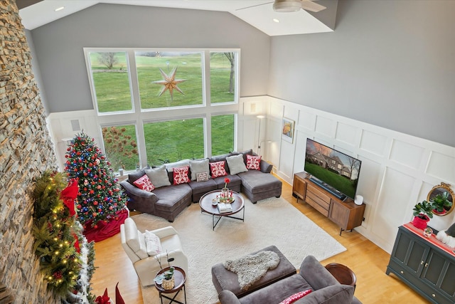 living room with ceiling fan, light hardwood / wood-style floors, and lofted ceiling