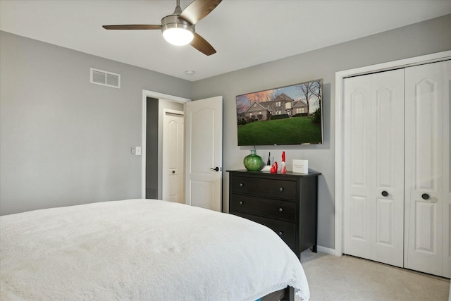 bedroom with ceiling fan, light colored carpet, and a closet