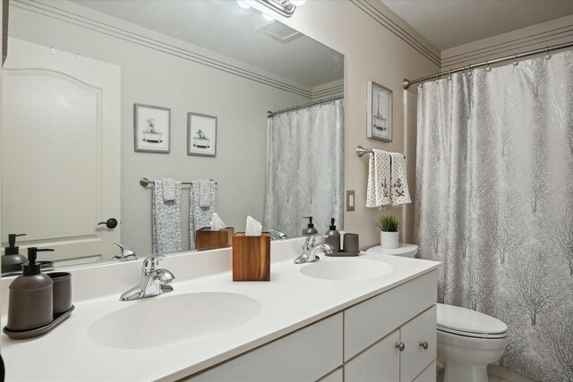 bathroom with a shower with curtain, vanity, toilet, and crown molding