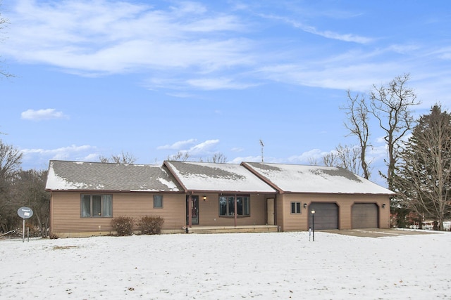 snow covered back of property with a garage