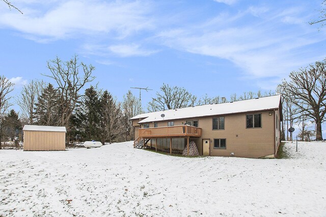 snow covered rear of property featuring a shed and a deck