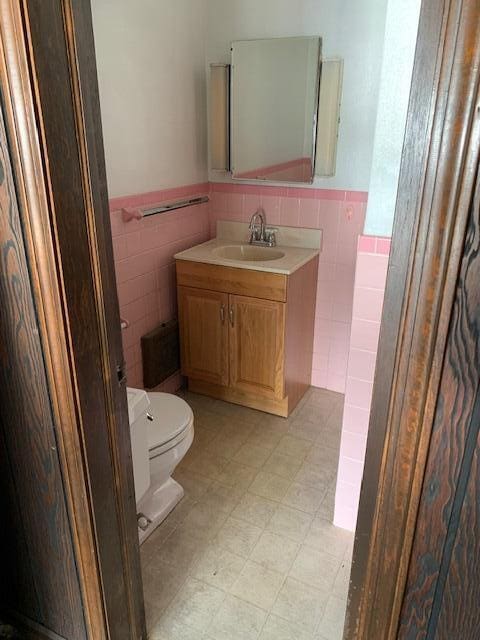 bathroom featuring vanity, tile walls, and toilet