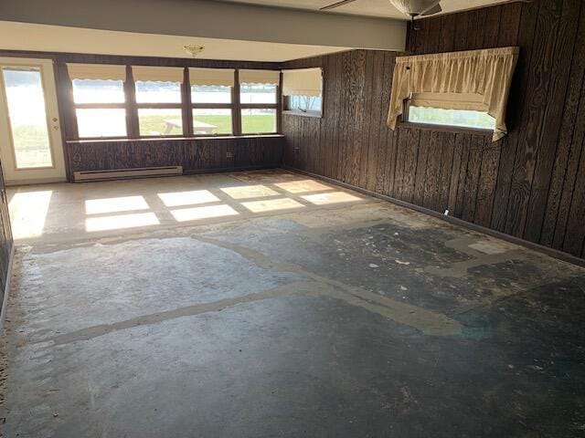 spare room with wooden walls, a healthy amount of sunlight, and a baseboard radiator