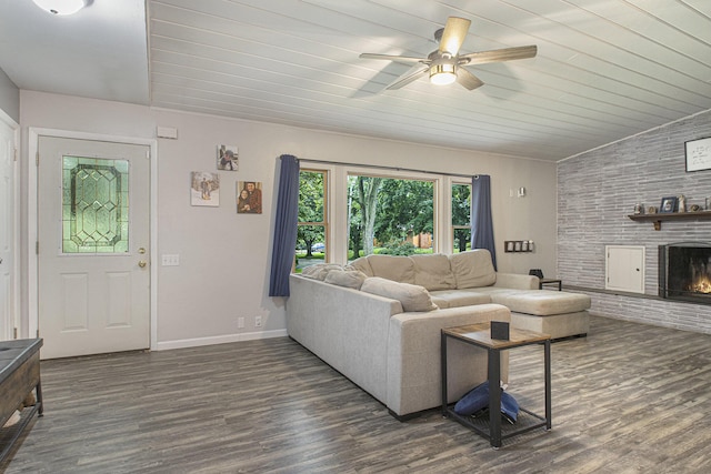 living room featuring a brick fireplace, dark hardwood / wood-style floors, vaulted ceiling, and ceiling fan