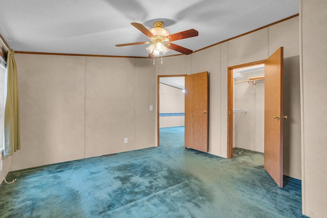 spare room featuring crown molding, ceiling fan, a textured ceiling, and dark colored carpet