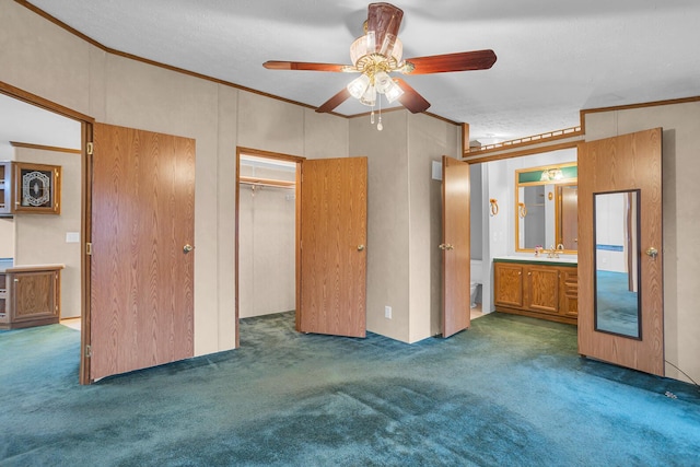 unfurnished bedroom featuring ensuite bathroom, ornamental molding, ceiling fan, dark colored carpet, and a closet