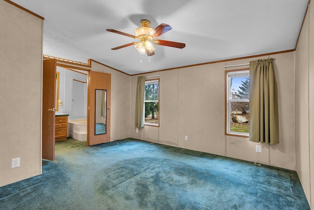 unfurnished bedroom featuring ensuite bathroom, ceiling fan, a textured ceiling, and multiple windows