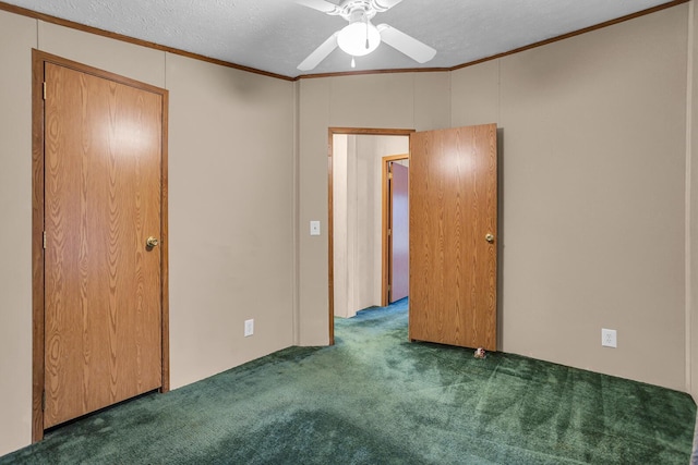 interior space featuring ceiling fan, dark carpet, a textured ceiling, and ornamental molding