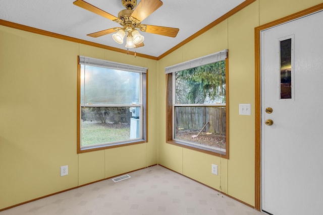 carpeted spare room featuring ceiling fan, ornamental molding, and vaulted ceiling