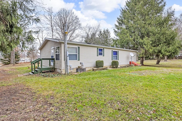 view of front of home with a front yard and central AC