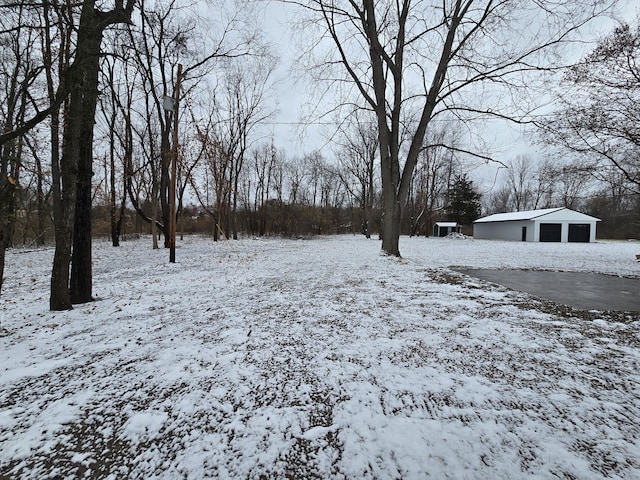 snowy yard featuring an outbuilding and a garage