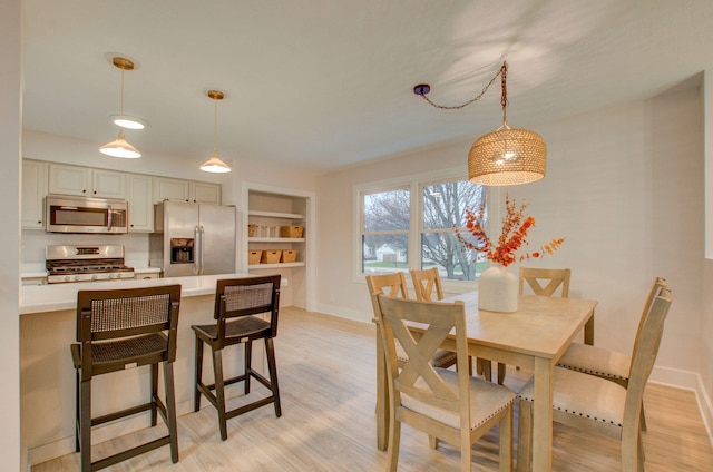 dining room featuring built in shelves and light hardwood / wood-style flooring