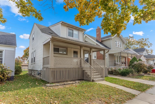 bungalow with covered porch and a front yard