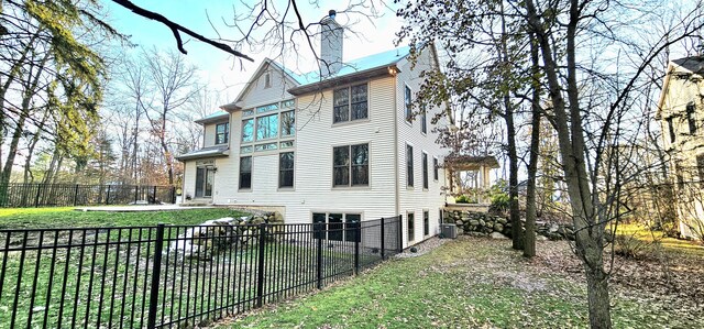 back of house with cooling unit and a lawn