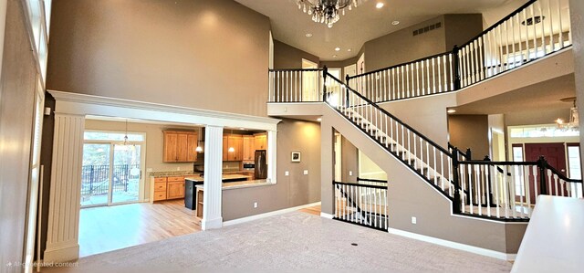 stairway with wood-type flooring, a towering ceiling, and a chandelier