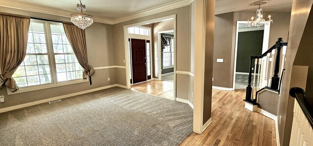 foyer entrance with a chandelier, light wood-type flooring, and crown molding