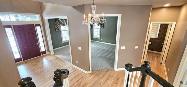 foyer with a notable chandelier, light hardwood / wood-style floors, and vaulted ceiling