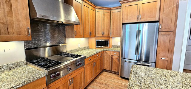 kitchen with light stone countertops, appliances with stainless steel finishes, and extractor fan