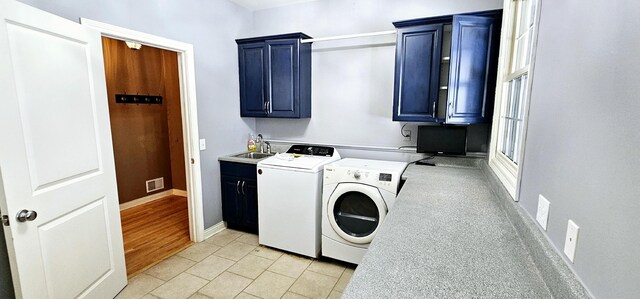 washroom with cabinets, sink, light hardwood / wood-style floors, and washing machine and clothes dryer