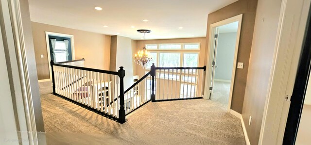 corridor featuring light carpet and a notable chandelier