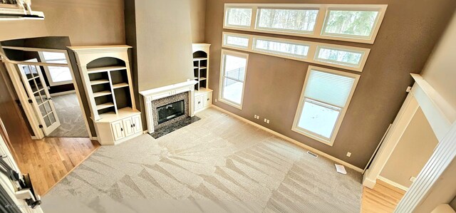 living room with a healthy amount of sunlight, light wood-type flooring, and a high ceiling