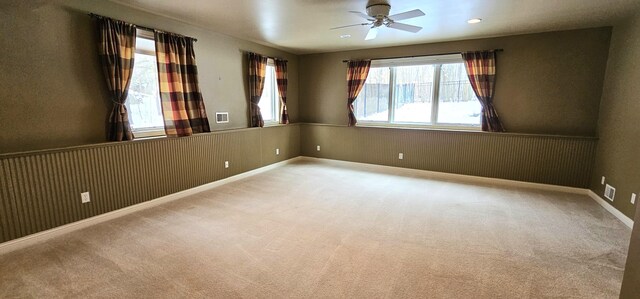 carpeted empty room featuring ceiling fan and plenty of natural light