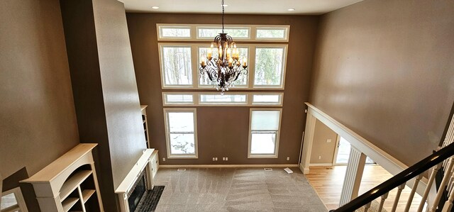 entryway featuring a chandelier, a towering ceiling, light hardwood / wood-style floors, and a wealth of natural light