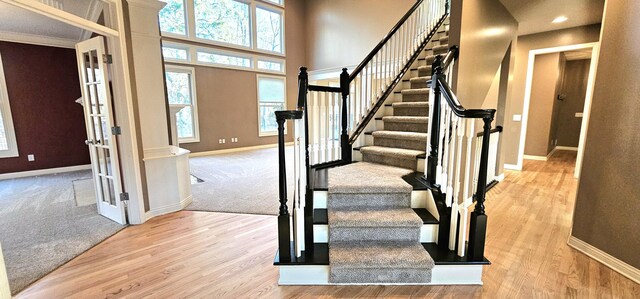 foyer entrance featuring french doors, ornamental molding, a high ceiling, and light wood-type flooring