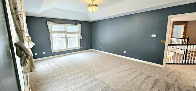 unfurnished room with light carpet, a tray ceiling, and an inviting chandelier