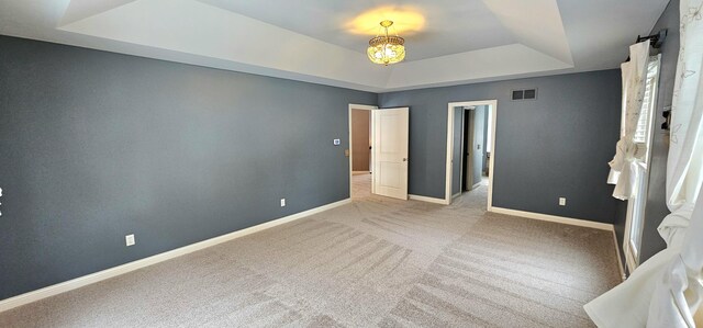 unfurnished room featuring a tray ceiling and light colored carpet